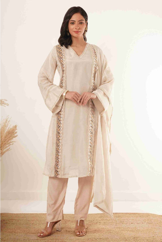 Woman wearing a cream-colored traditional outfit with a dupatta on a white background