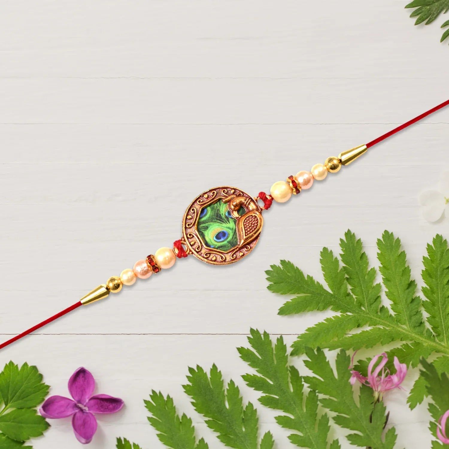 Elegant Rakhi With Peacock Feather Design And Pearl Bead Accents On Red Thread - warehousetech13
